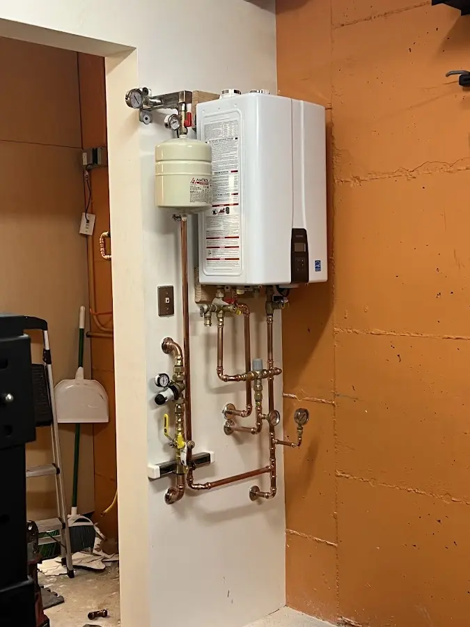 Plumbing technician inspecting water heater connections in Lake City